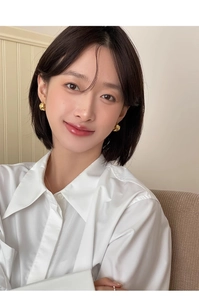 Close-up of a model wearing irregular knotted gold hoop earrings in a minimalist style