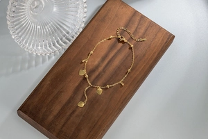 Detail of gold heart charms and round beads on a minimalist chain with lobster clasp