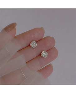 Close-up of gold square stud earrings with pavé zircons on white lace background