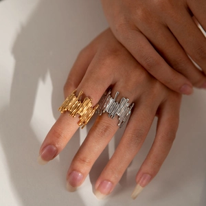 Dettaglio macro della texture lavica irregolare su anelli in acciaio inossidabile oro e argento