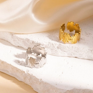 Dettaglio macro della texture a farfalla traforata su anelli regolabili oro e argento