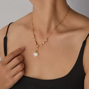Detail of heart-shaped mother of pearl pendant on golden chain with rectangular gems