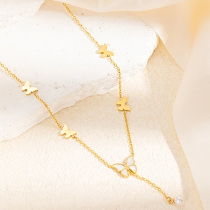 Detail of gold butterfly necklace featuring white mother of pearl inlay and pearl drop