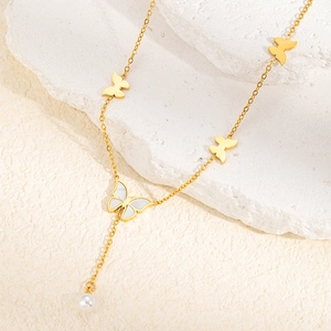Detail of gold butterfly necklace with white mother of pearl inlay and pearl drop charm