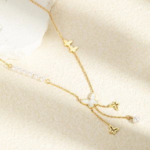 Detailed macro view of golden butterfly necklace with pearl tassels on stone
