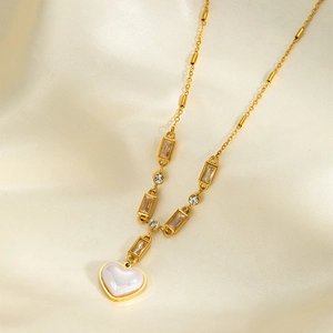 Close-up of golden heart pendant with iridescent inlay and cubic zirconia chain on silk