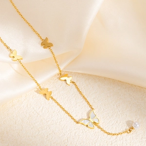 Detail of gold butterfly necklace with mother of pearl inlay and a white hanging pearl