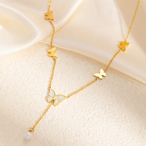 Close-up of golden butterfly necklace with white shell inlay and elegant pearl drop tassel