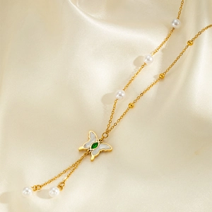 Elegant gold butterfly pendant necklace with pearls and green gemstone on silk background