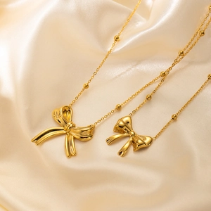 Macro detail of polished stainless steel bow pendants on elegant champagne silk background