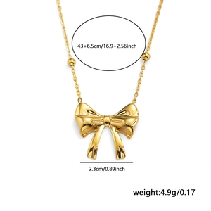 Gold bow pendant necklace with bead chain and dimensions in a minimalist white background