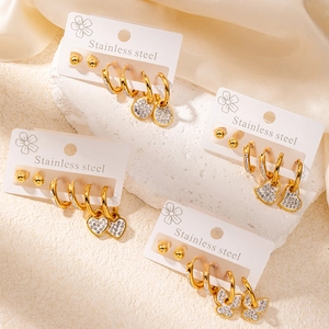 Détail du set de boucles d'oreilles en acier doré avec zircons en forme de cœur et papillon