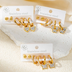 Détail du set de boucles d'oreilles en acier doré avec breloques cœur, papillon et étoile