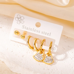 Trois paires de boucles d'oreilles en acier doré, émail blanc et breloques cœur