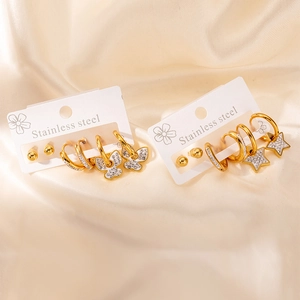 Détail de boucles d'oreilles en acier doré avec pendentifs papillon et étoile en zircon