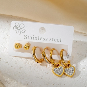 Détail d'un ensemble de trois boucles d'oreilles en acier doré avec strass et cœurs