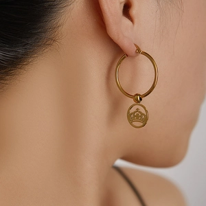 Detailaufnahme goldener Edelstahl-Ohrring mit einem hohlen Kronenanhänger für Damen