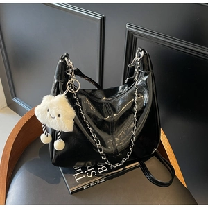 Detail of black glossy hobo bag with silver chain and white plush cloud pendant charm