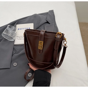 Dettaglio della borsa a secchiello marrone scuro con chiusura a scatto dorata