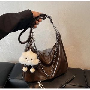 Detail of dark brown glossy PU leather tote bag featuring a cute white cloud plush pendant