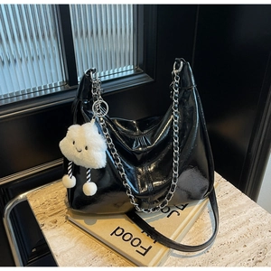 Detail of black faux leather tote with silver chain and white cloud plush charm accessory