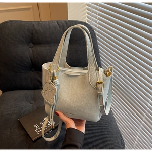 Detail view of light blue lychee pattern bucket bag with cute dog pendant and gold hardware