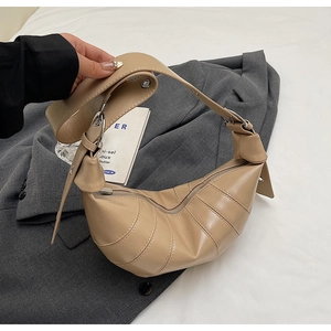 Detail of beige croissant bag with segment stitching and adjustable strap on blazer