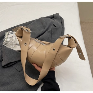 Detailed view of segmented stitching on beige croissant bag with metal eyelet strap