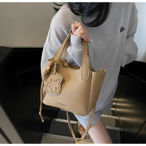 Detail of camel bucket bag with lychee grain leather texture and dog charm decoration