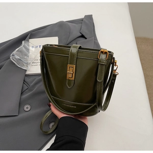 Dettaglio borsa a secchiello verde scuro con chiusura a rotazione dorata e tracolla