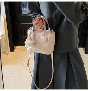 Detail of pink embossed bucket bag featuring cartoon prints and plush pendant charm