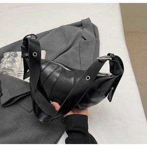 Detail of black leather crescent bag with stitching, wide eyelet strap and silver zipper