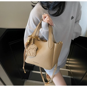 Detail view of khaki bucket bag featuring litchi texture leather and a cute dog pendant