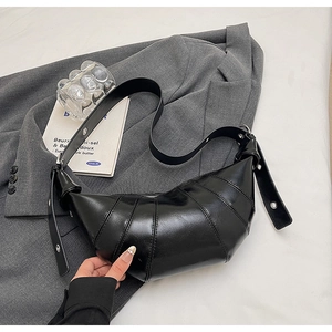 Detail of black croissant bag with segment stitching and adjustable wide shoulder strap