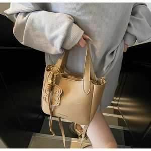 Detail of khaki bucket bag with lychee texture leather and a cute dog charm accessory
