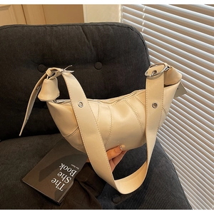 Detail of cream croissant bag featuring pleated texture and silver metal buckle