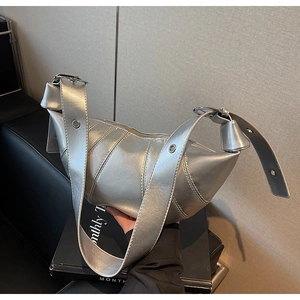 Close-up of metallic silver croissant bag with pleated details and industrial strap