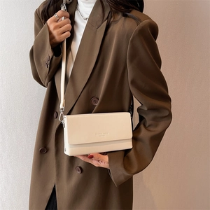 Chic cream white rectangle crossbody bag in vegan leather worn with a brown blazer