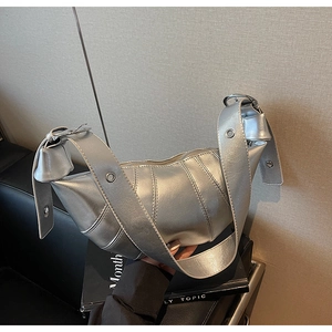 Detail of silver metallic croissant bag with stitched panels and grommet strap