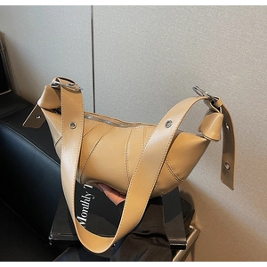 Detail of beige croissant bag with pleated leather texture and wide grommet strap