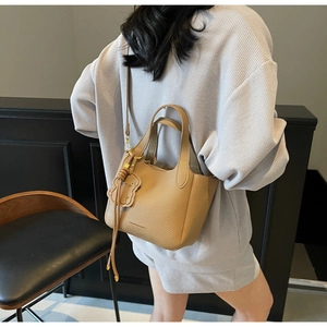Close-up of light brown lychee grain bucket bag with a cute leather dog charm