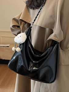 Minimalist black glossy hobo tote bag with silver chain and white plush charm on model