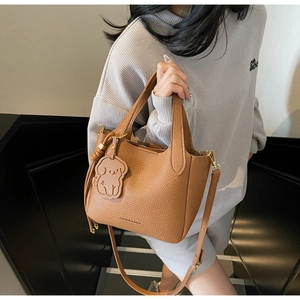 Detail of brown litchi pattern bucket bag with cute dog charm on a crossbody strap