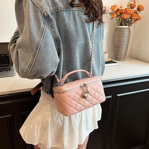 Chic pink quilted box bag with chain strap and heart charm shown in a lifestyle setting