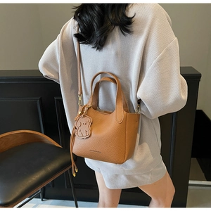 Detail of vintage brown pebble leather bucket bag with a cute dog pendant and strap