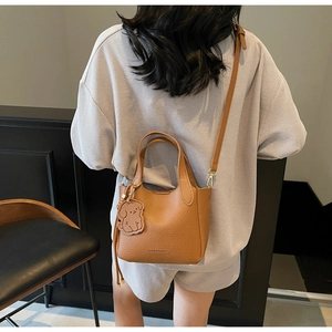 Caramel pebble leather bucket bag with puppy charm detail and adjustable shoulder strap