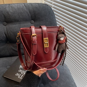 Borsa a secchiello bordeaux con dettagli dorati e un simpatico ciondolo a forma di orso