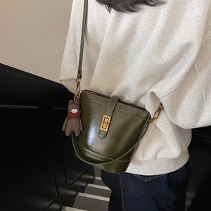 Borsa a secchiello in pelle verde oliva con chiusura dorata e ciondolo a orsetto