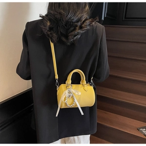 Sac Boston jaune vif à texture litchi porté avec un costume noir dans un escalier chic