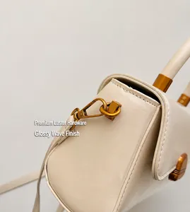 Close-up of off-white leather handbag with vintage gold metal hooks and stitching details